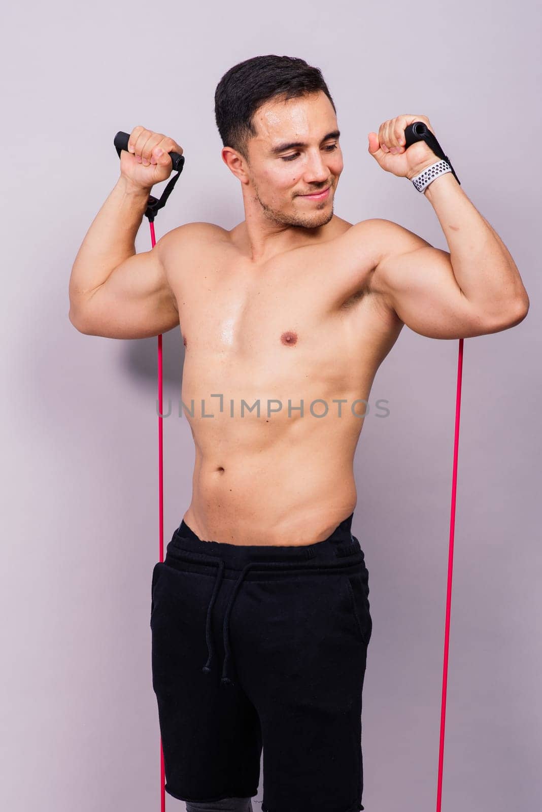 Athletic man skipping with jump rope on grey background. Best cardio workout