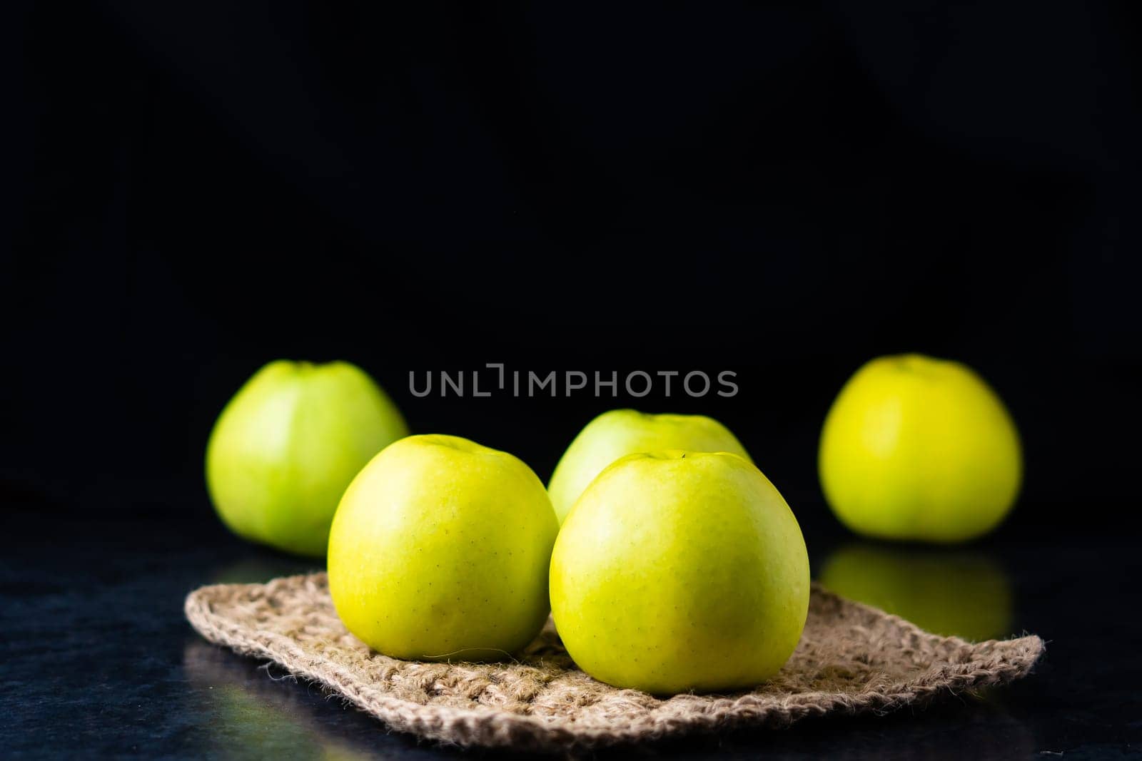 A ripe green apple fruits on dark stone table. Top view with copy space. Flat lay by Zelenin