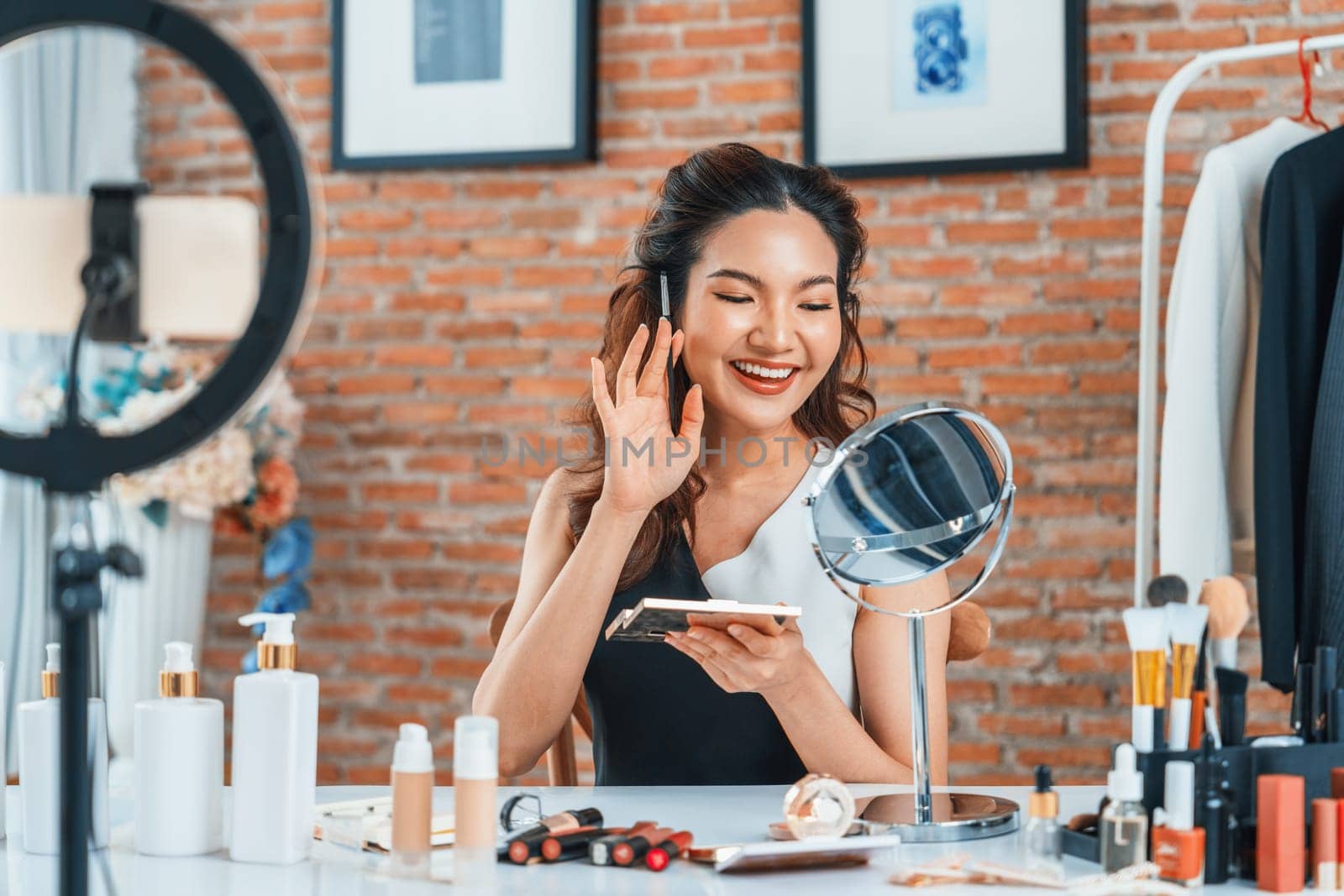 Woman influencer shoot live streaming vlog video review makeup uttermost social media or blog. Happy young girl with cosmetics studio lighting for marketing recording session broadcasting online.