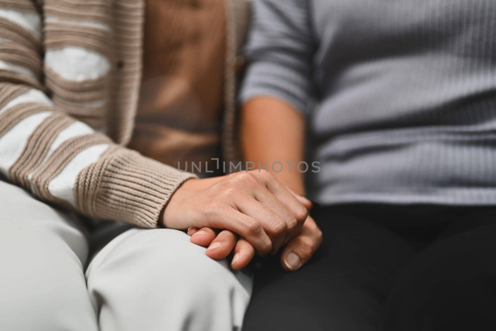 Grown up daughter holding hands of old mother for giving support, empathy and understanding.