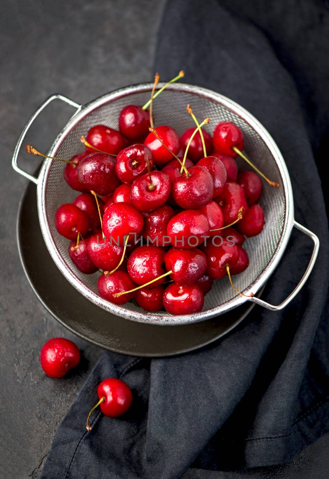 Ripe sweet cherry berry with leaves on a black wooden board