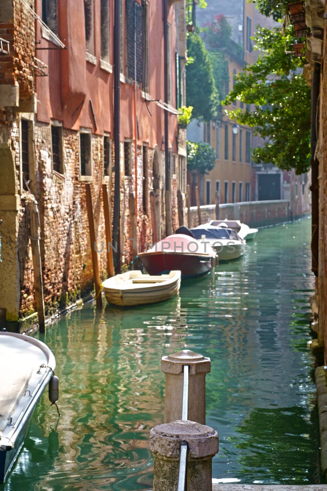 Sunny channel in Venice with boats parked around