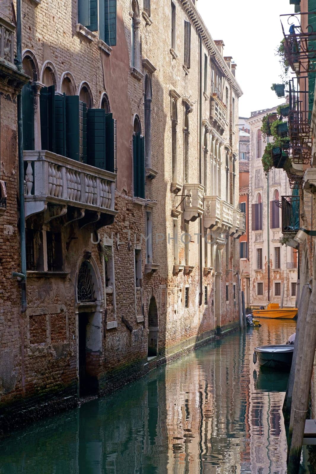 Sunny channel in Venice with boats parked around