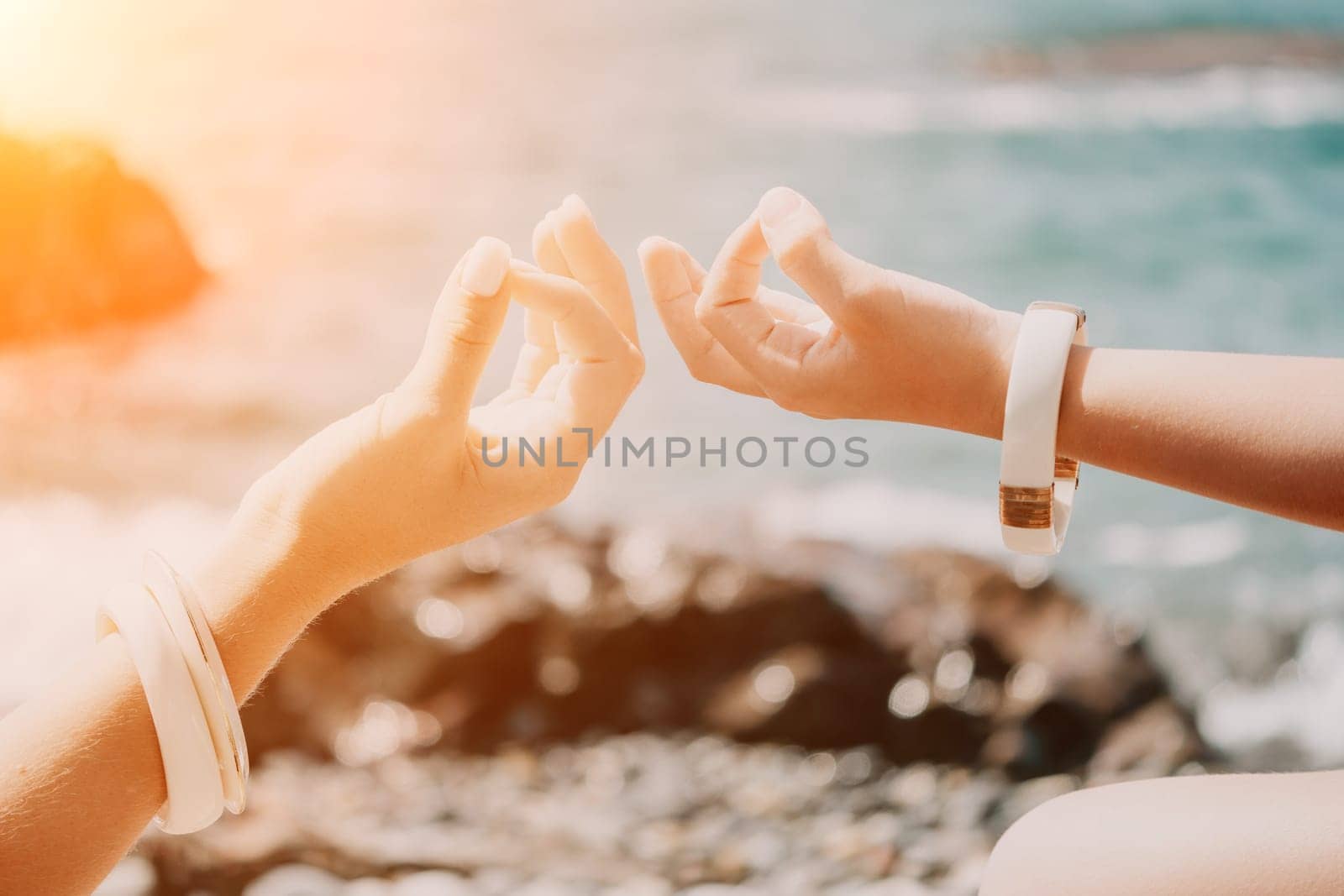 Close up Yoga Hand Gesture of Woman Doing an Outdoor meditation. Blurred sea background. Woman on yoga mat in beach meditation, mental health training or mind wellness by ocean, sea by panophotograph