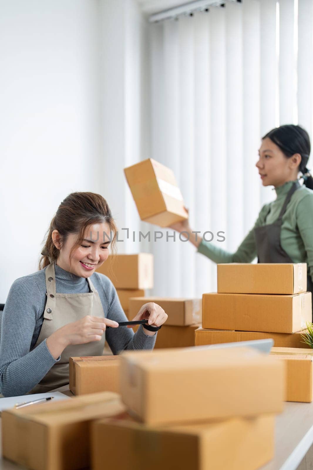 Small business SME owner, Two young Asian business owner woman prepare parcel box and check online orders of product for deliver to customer, packaging, Shopping Online concept.