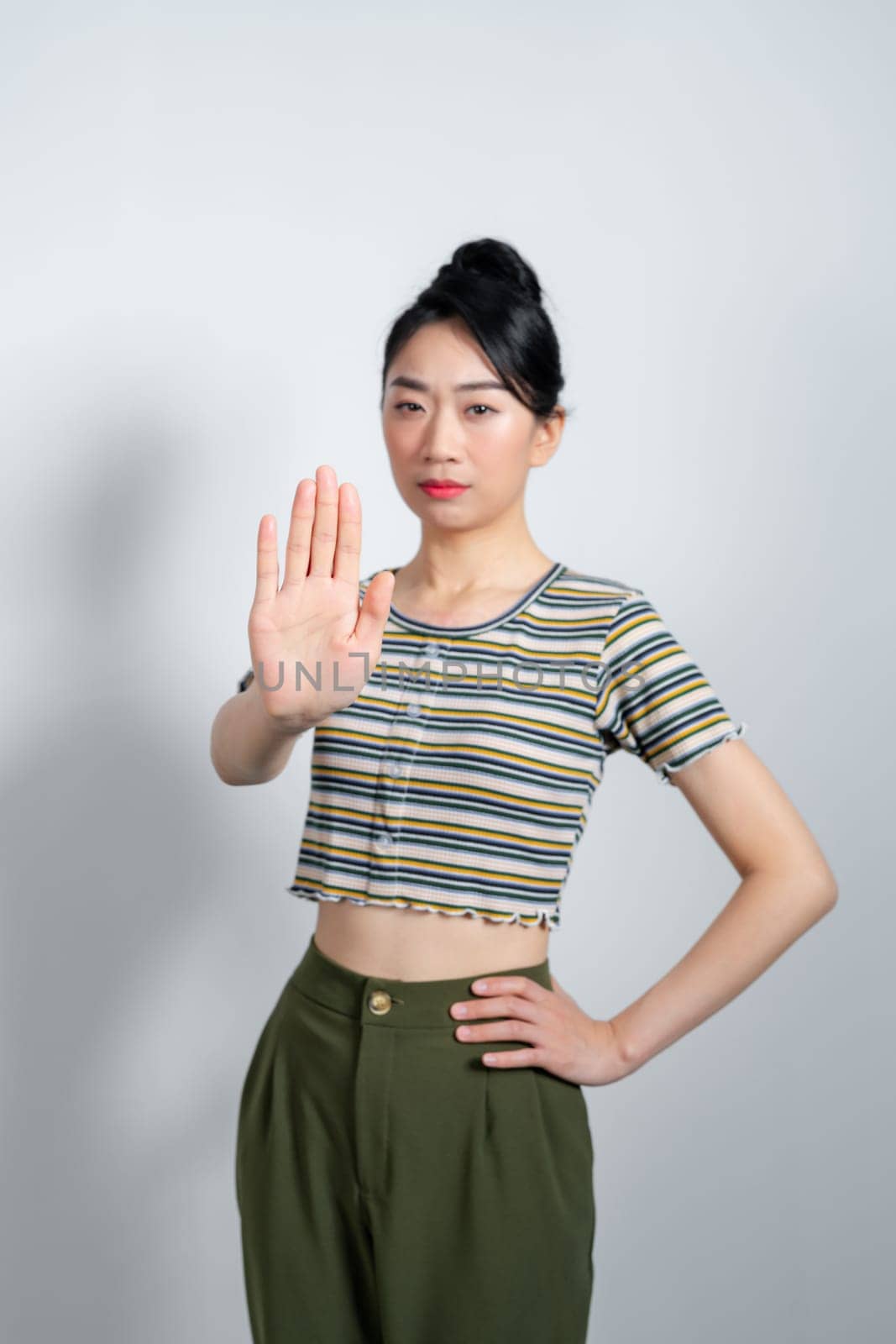 asian young woman looking serious, stern, displeased and angry showing open palm making stop gesture