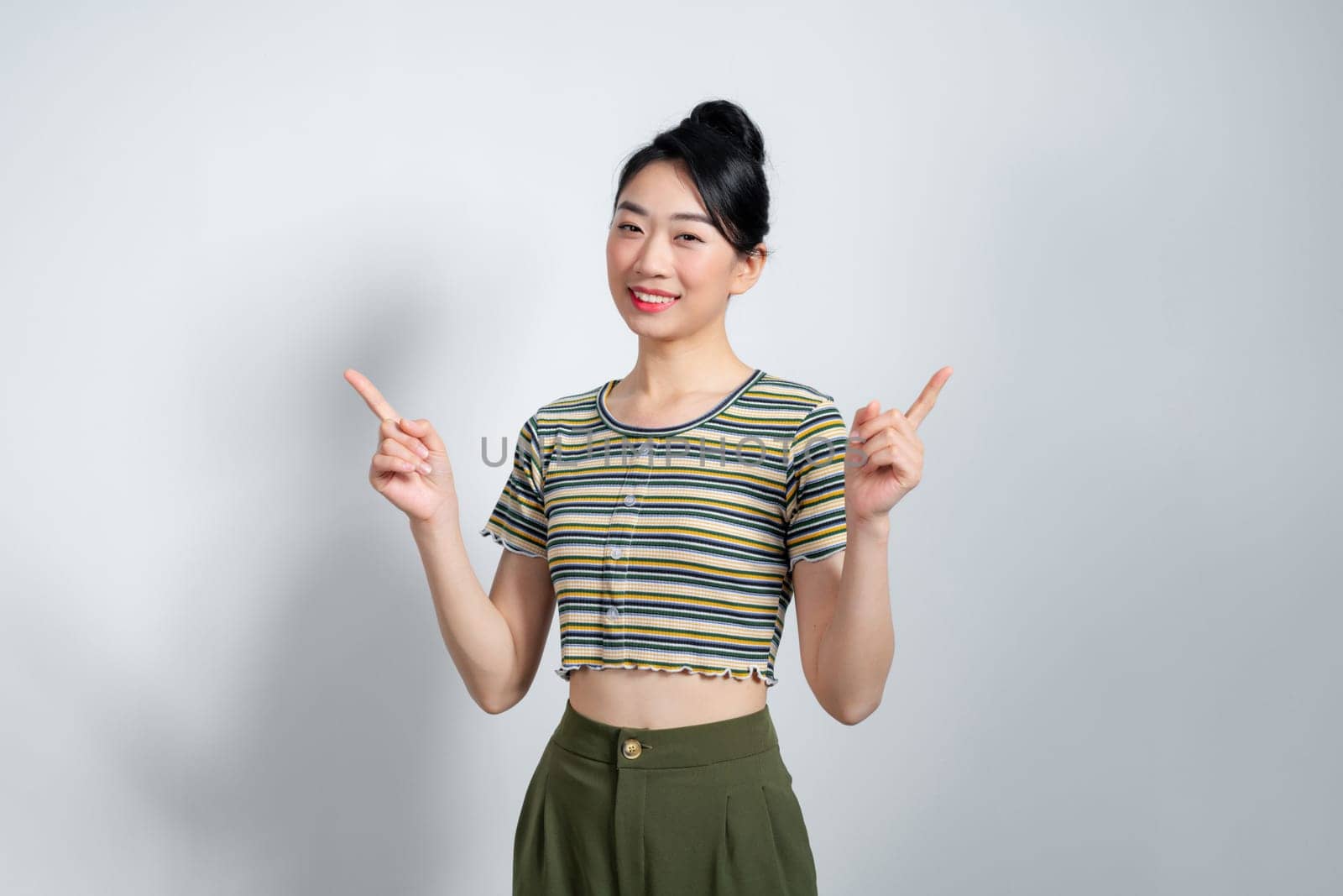 Beautiful young Asian woman pointing two side to copy space with smiley face and happy