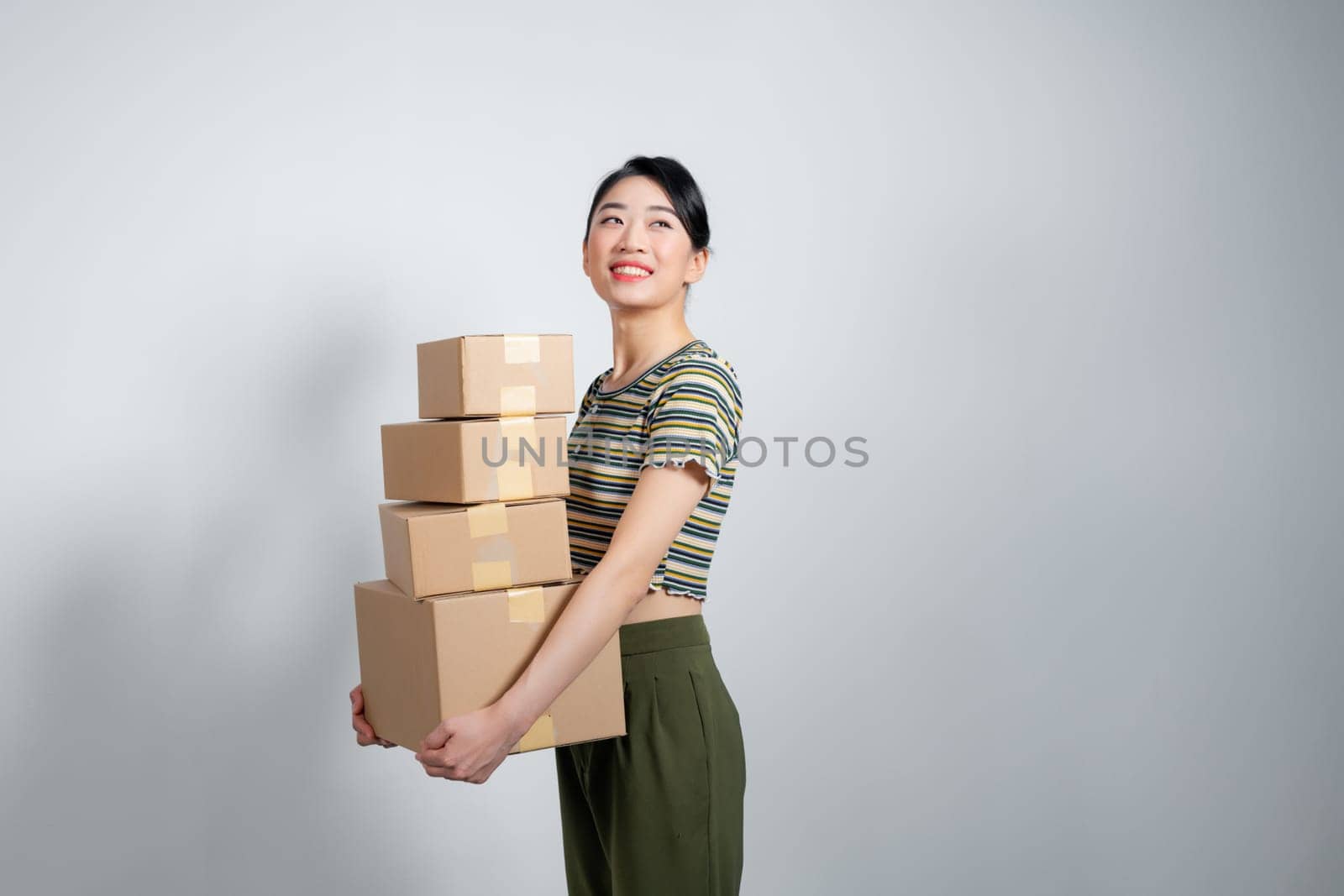 Happy Asian girl holding package parcel boxs isolated on gray background.