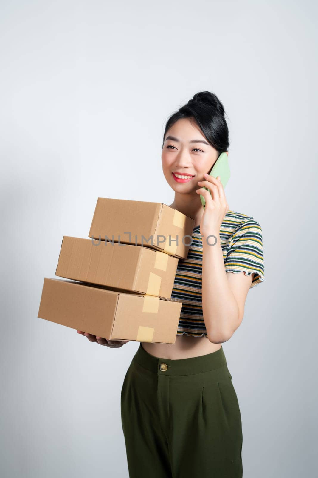 woman carrying cardboard box stack and talking on the mobile phone by makidotvn