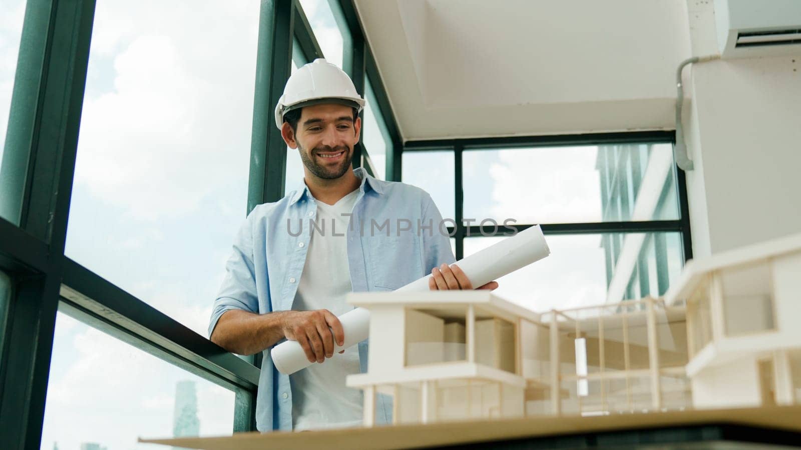 Smart civil engineer standing, walking while looking at house model and architectural equipment. Engineer with safety helmet standing near city view while standing near building model. Tracery