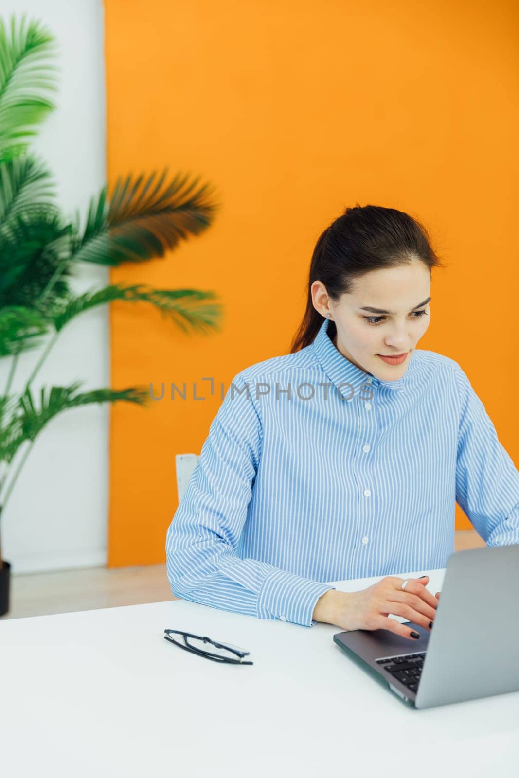 Image of young pleased happy cheerful cute beautiful business woman sit indoors in office using laptop by Simakov