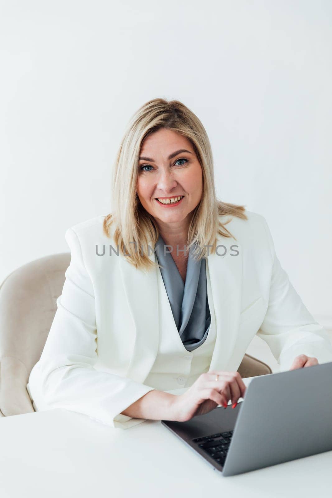 works online on a laptop computer, prints text to a project partner. The student manager is sitting on a chair of a young woman of Caucasian appearance. a favorite work, a comfortable business suit