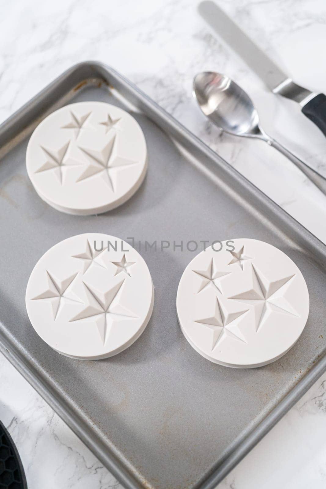 Filling silicone mold with white melted chocolate to make chocolate chocolate stars for American flag mini cupcakes.