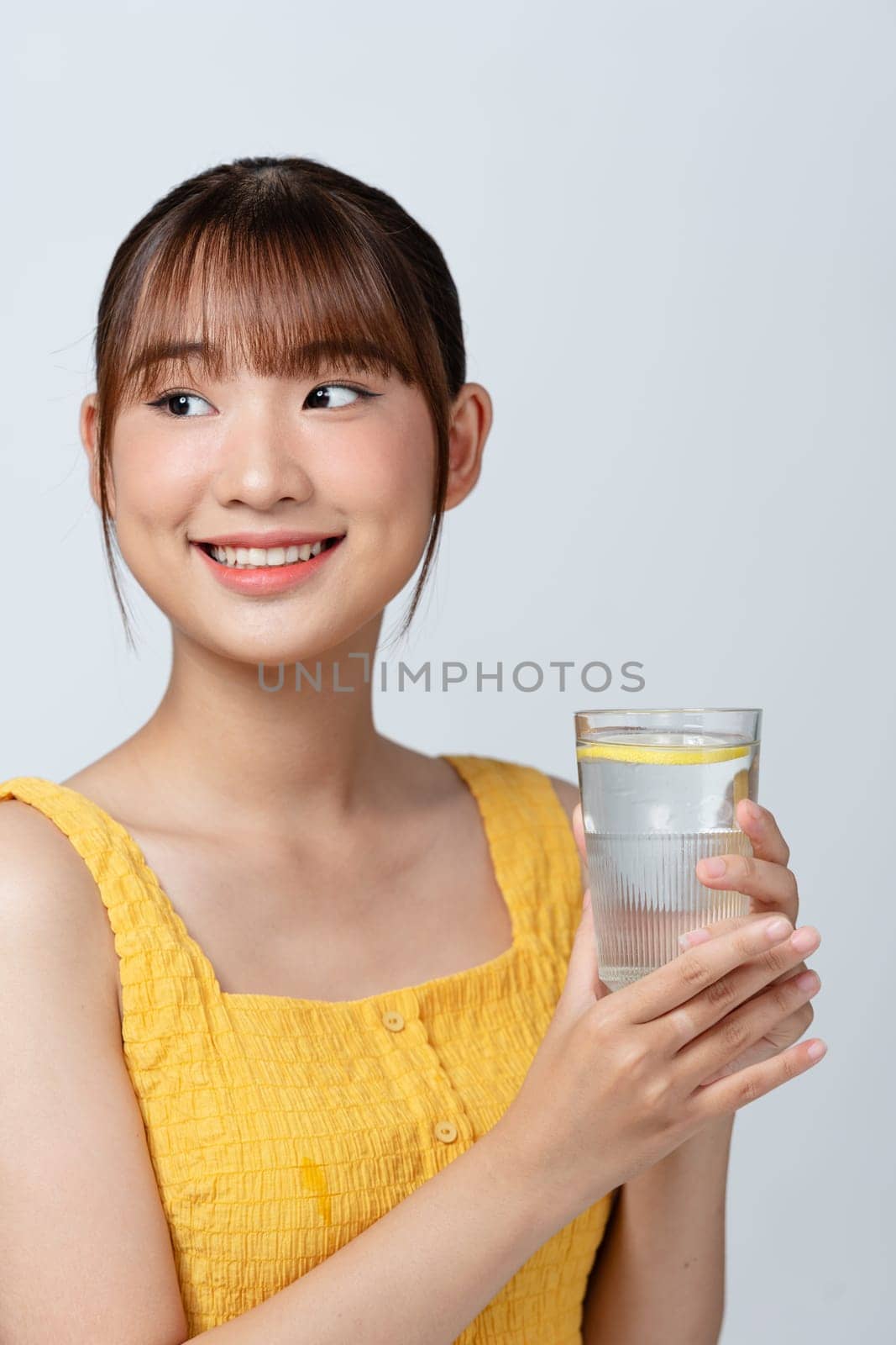 Vitamin Shot. Attractive asian woman drinking mineral water with lemon from glass by makidotvn