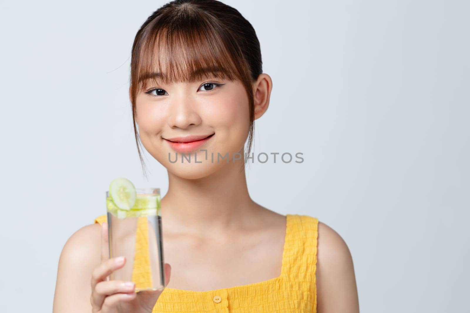 Pleasant woman holding glass of water with cucumber slices by makidotvn