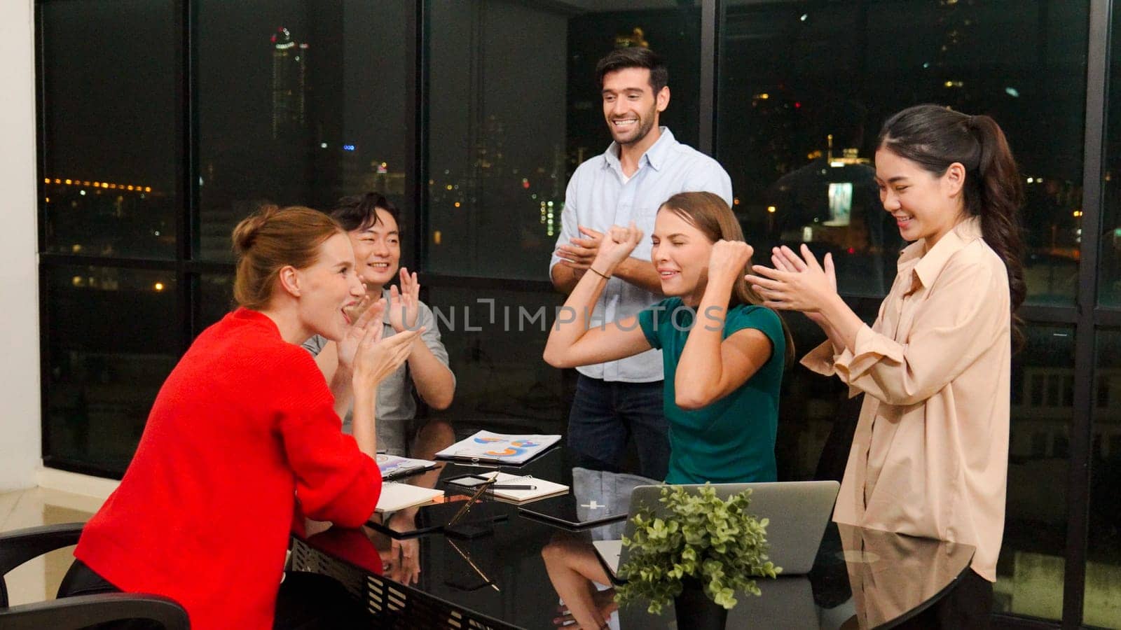 Businesspeople putting hands together and clapping hands to celebrate successful project at modern office with night city view. Group of manager with stacks of hands. Teamwork, trust. Tracery