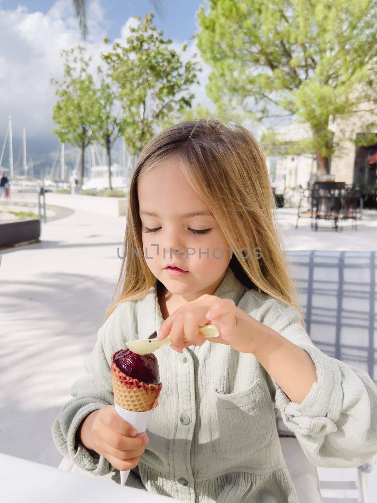 Little girl picks up popsicles in a waffle cone with a spatula. High quality photo