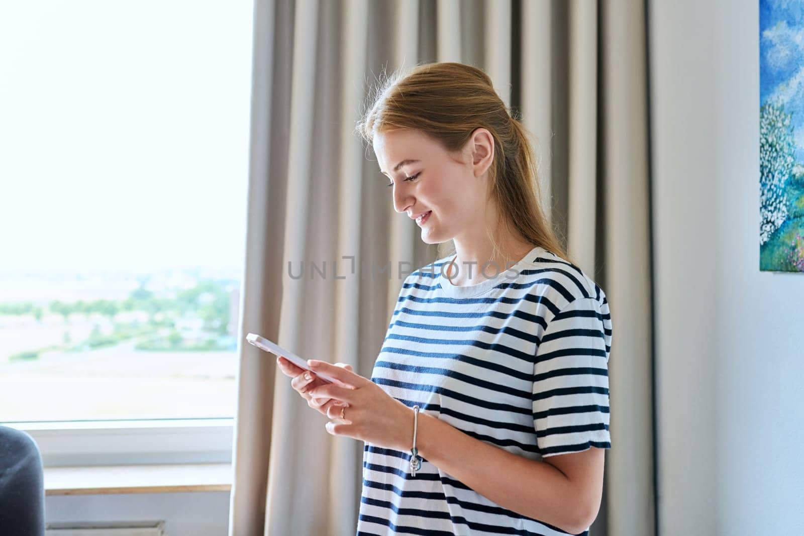 Young teenage female using smartphone, at home by VH-studio