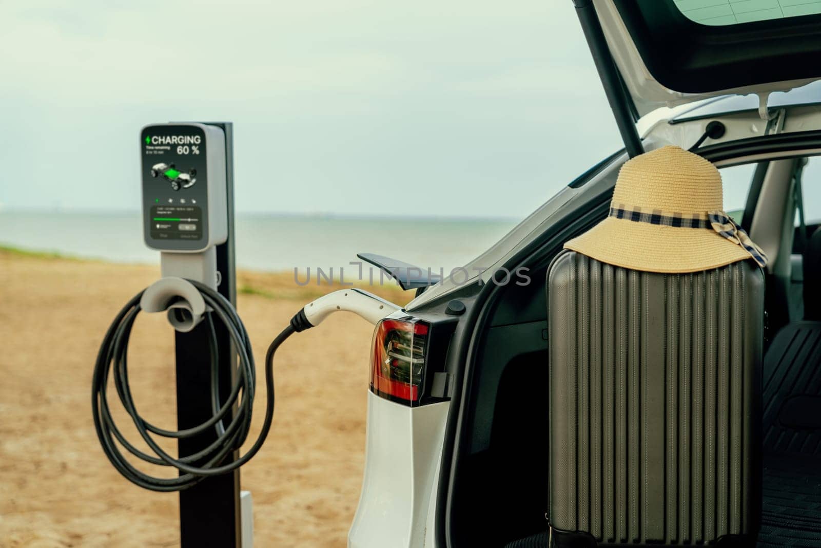 Road trip vacation to the beach with electric car recharging battery. Perpetual by biancoblue