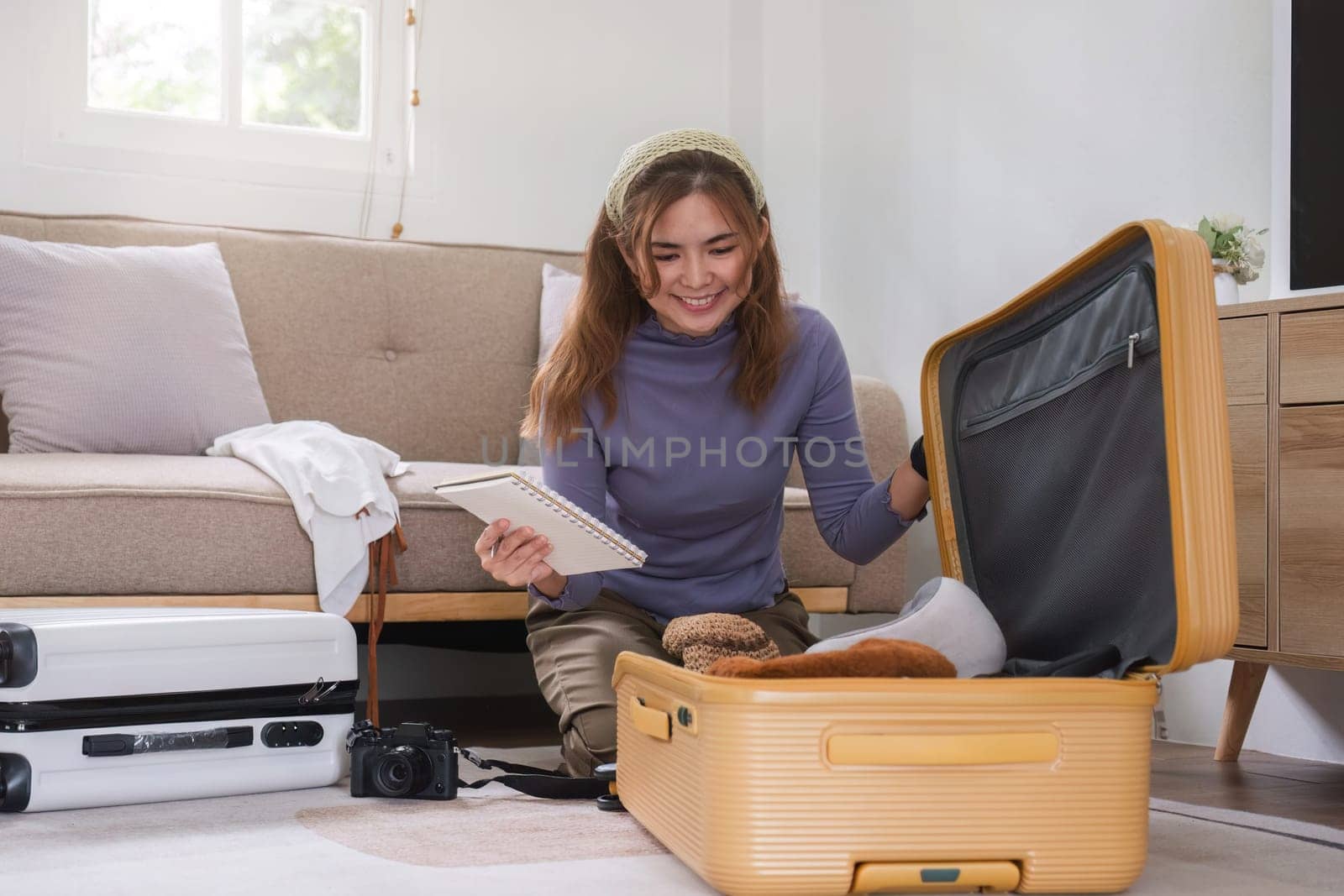 Attractive Asian woman packs her suitcase, packing her belongings, clothes and travel documents before going on vacation. Lifestyle concept.