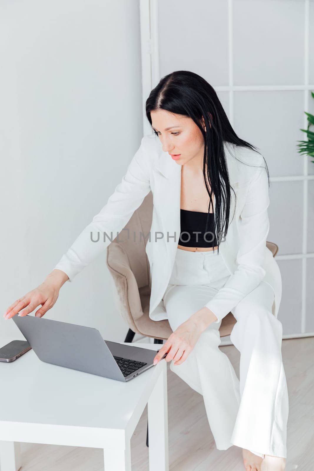 brunette woman in white suit working with laptop online