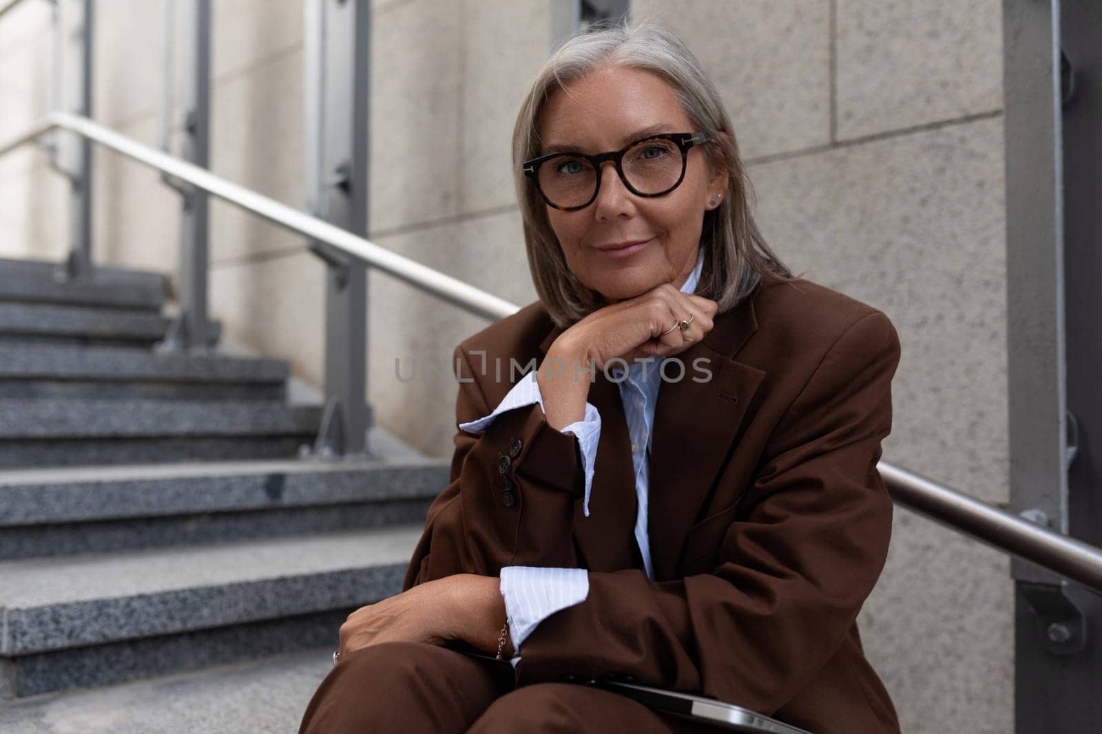 portrait of a successful well-groomed gray-haired middle-aged business woman dressed in a stylish suit in an urban environment.