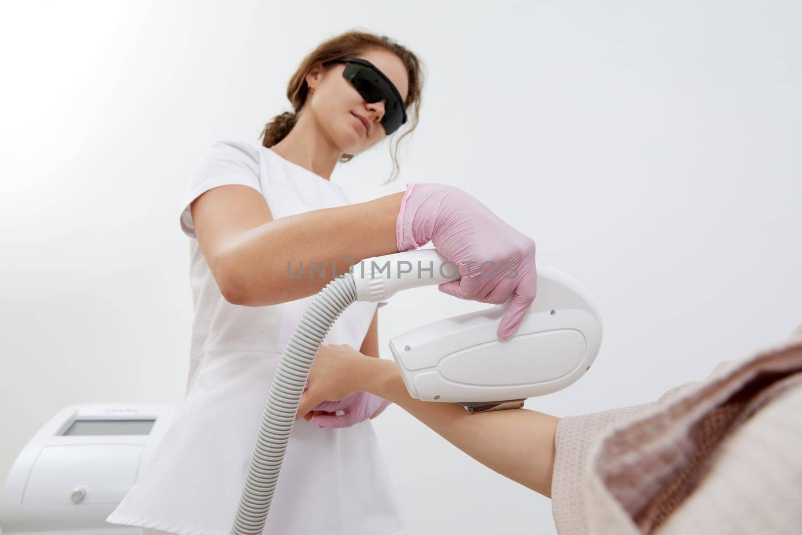 A woman in a salon setting gets her hands treated with laser hair removal