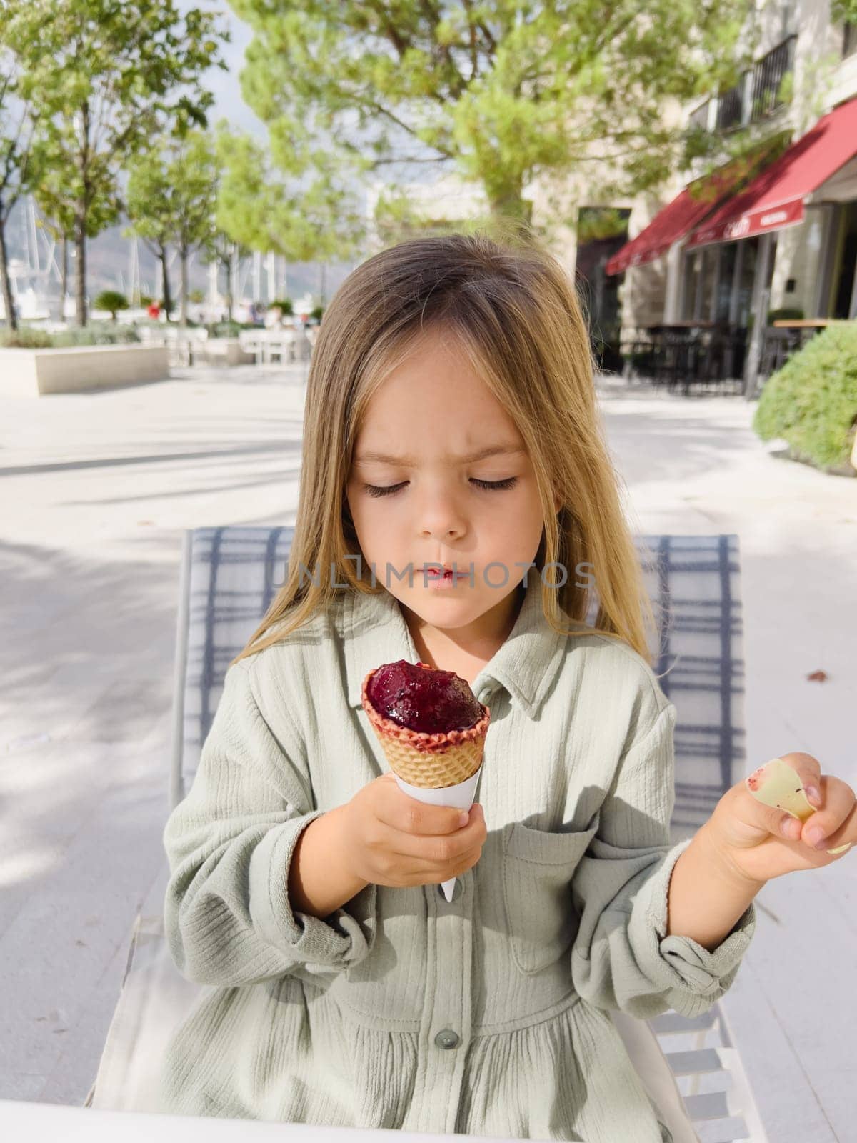 Little girl examines popsicles in a waffle cone in her hand. High quality photo