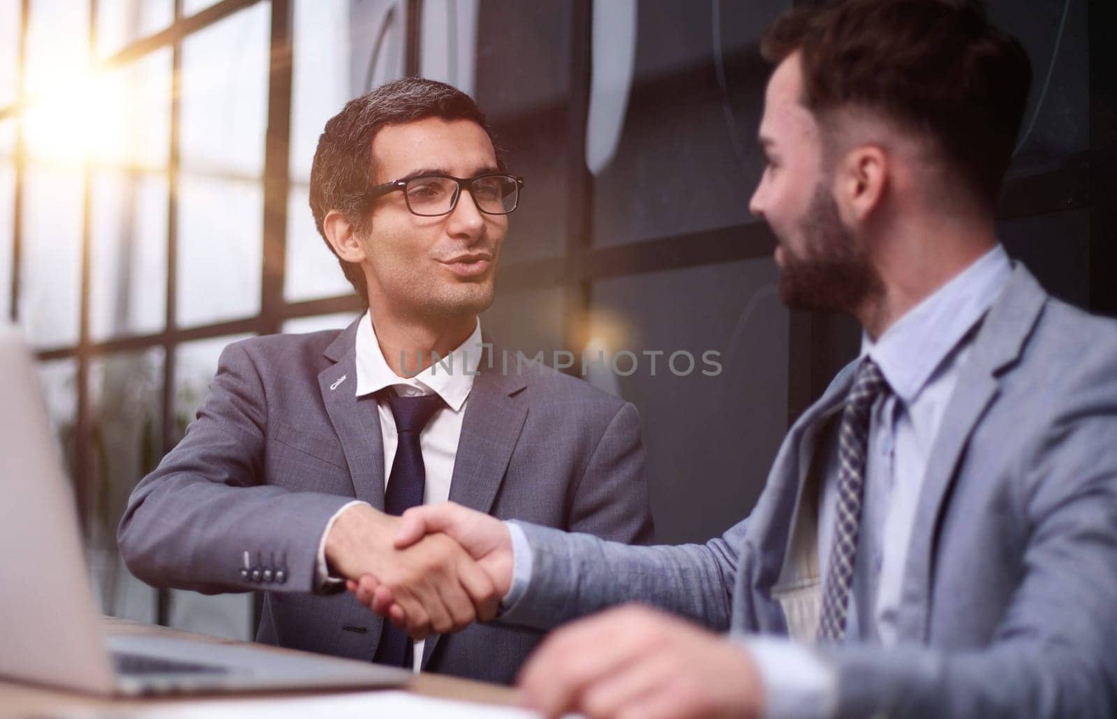 Two Businessmen Having Meeting Around Table In Modern Office by Prosto