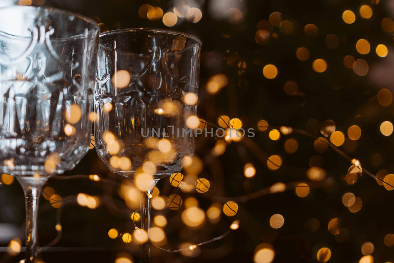 Champagne glasses, New Year decor. New Year's festive setting, family holidays.Two glasses of champagne are on the table against the background of New Year's decorated tree