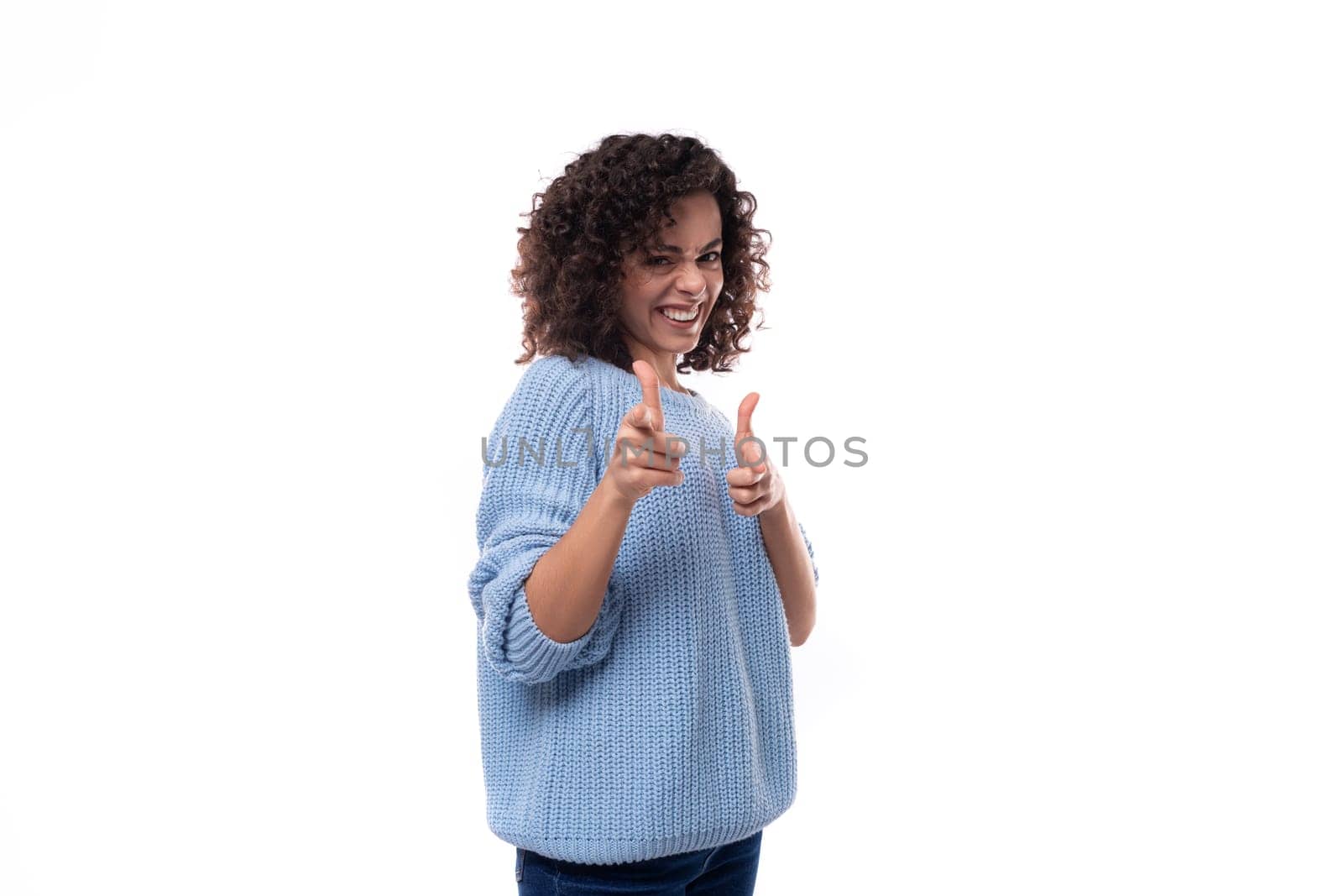portrait of a charming young caucasian woman with curly dark hair dressed in a casual warm blue blouse on a white background with copy space.