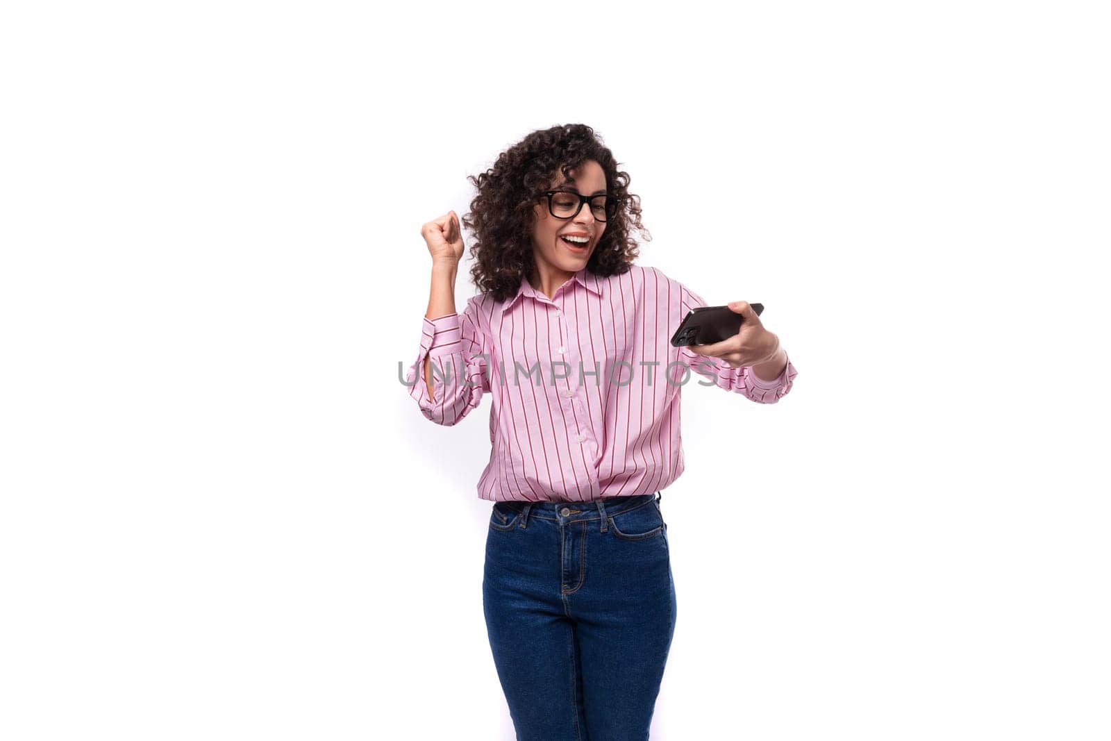 young charming caucasian woman with curly hair dressed in a striped shirt watches video on the phone.