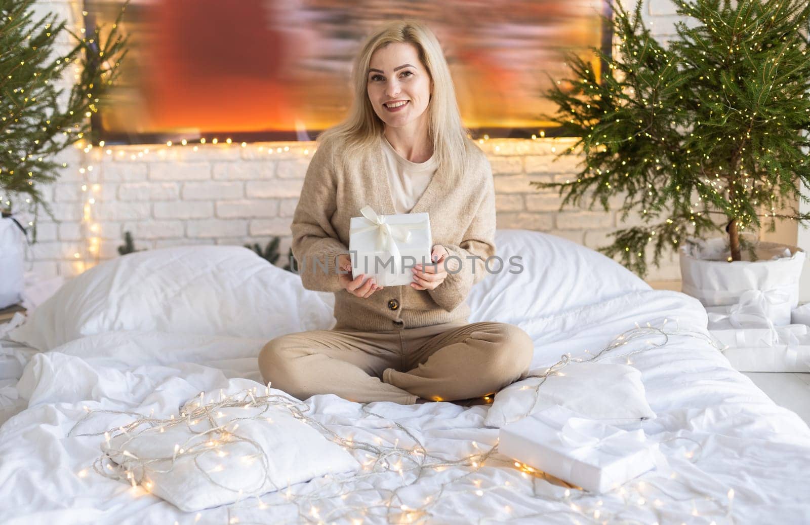 Beautiful young woman looking photobook in front of Christmas tree.