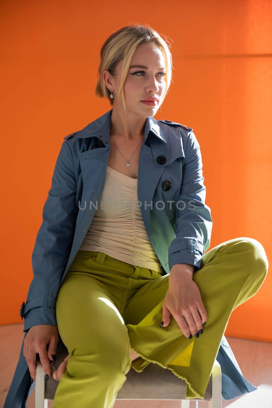 blonde woman in autumn raincoat on orange background