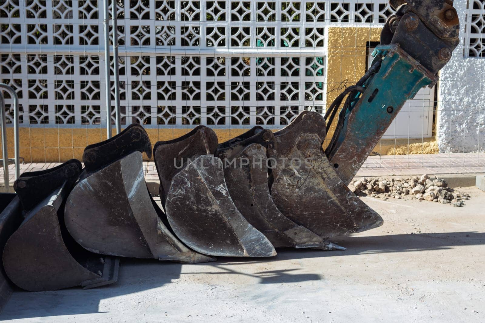 many buckets from an excavator stand on the road outside, close-up and space for an inscription by PopOff