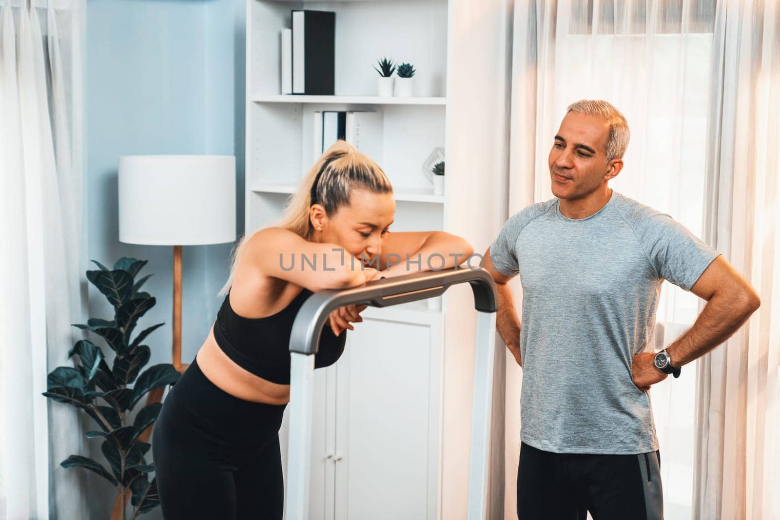 Active senior couple running on tread running machine at home together as fitness healthy lifestyle and body care after retirement for pensioner. Clout