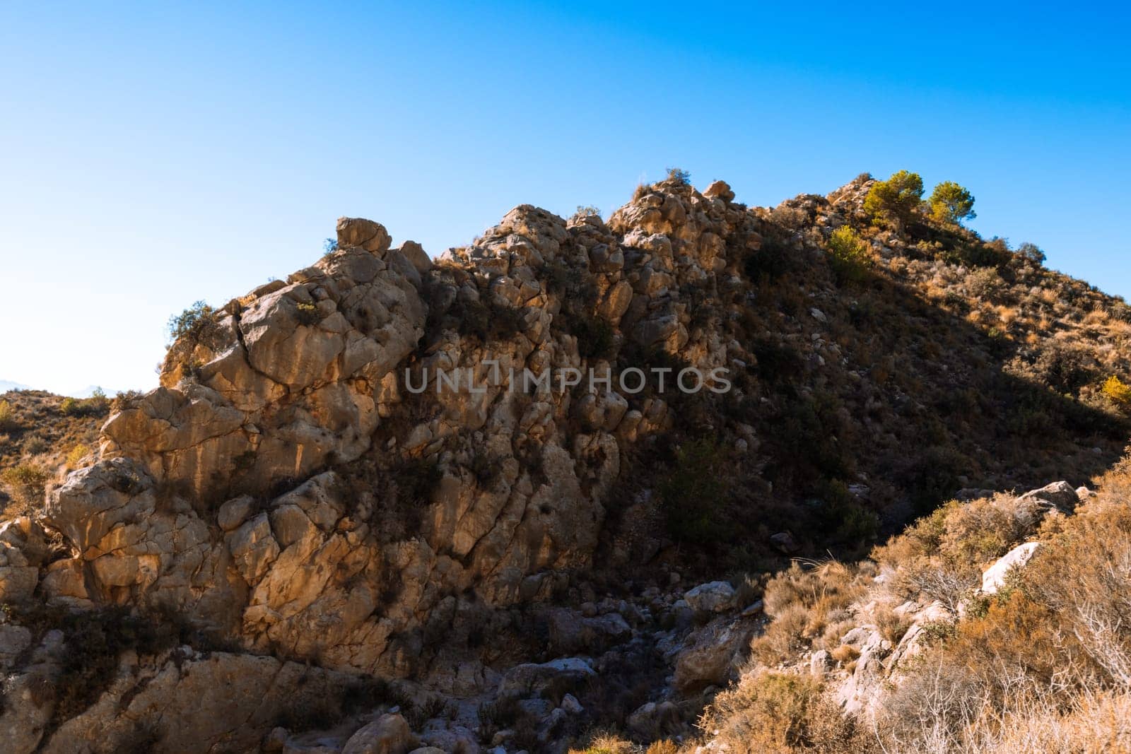 Rock, close up isolated photo of rich golden geometric mountain wall against blue sky for abstract industrial background texture. High quality photo