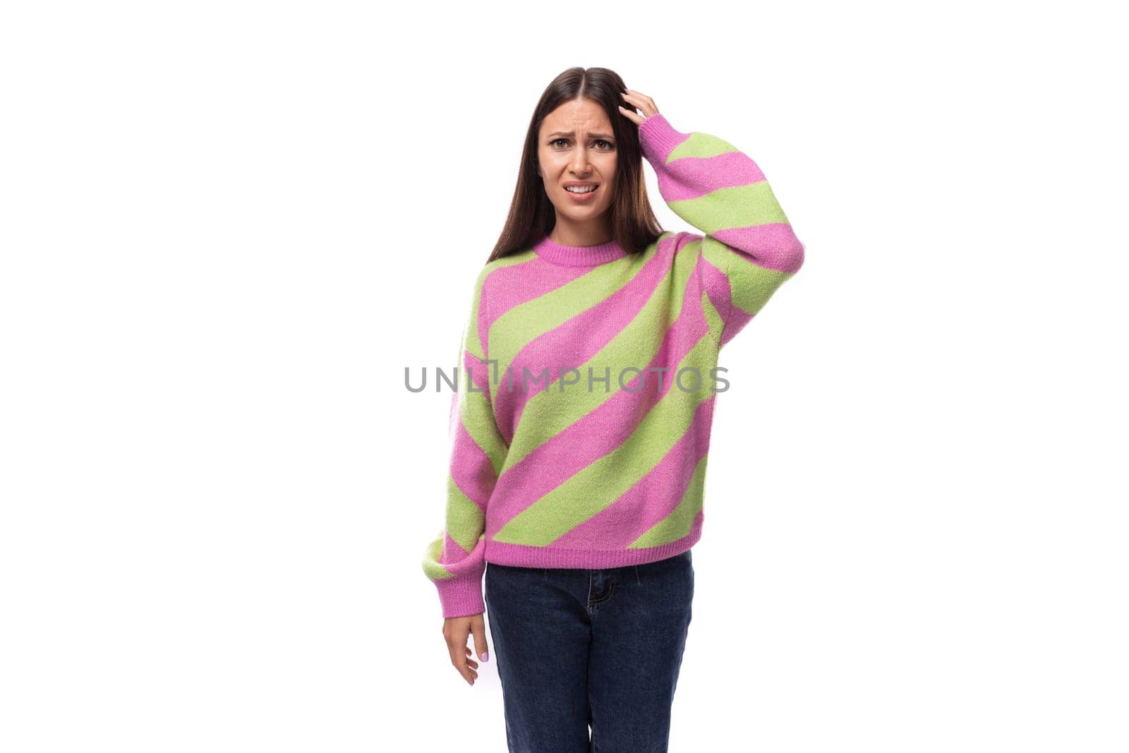 pretty upset confused young brunette woman in a striped pink blouse on a white background with copy space.