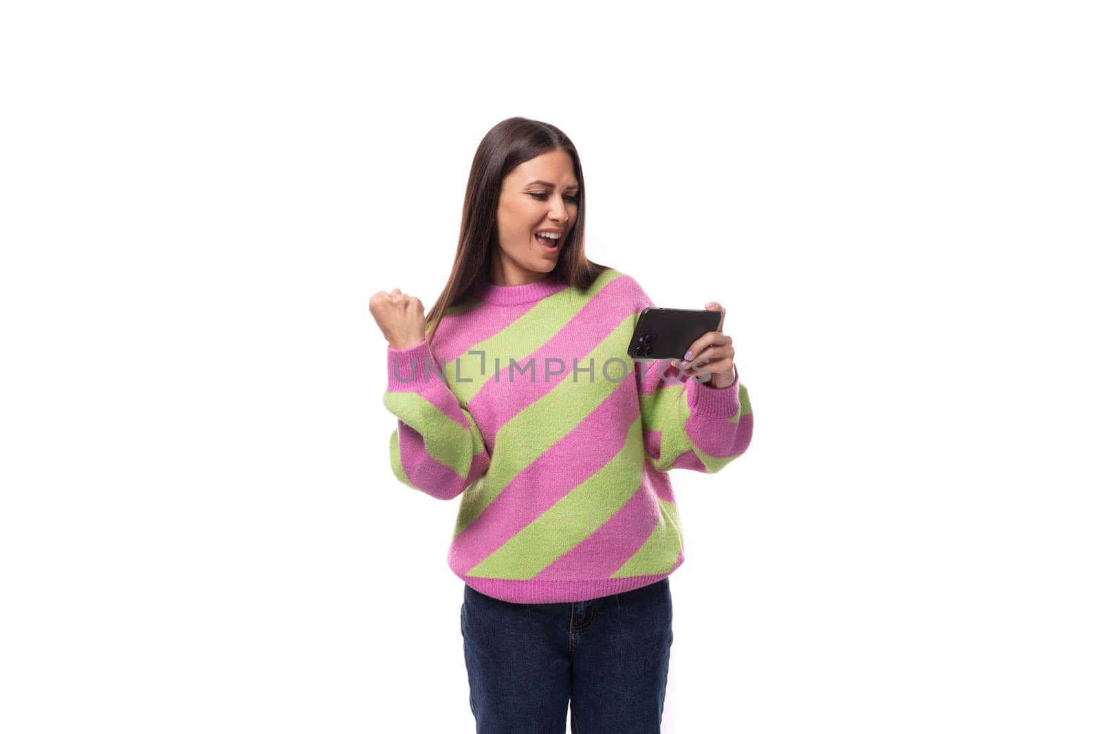 pretty young brunette woman in a striped pink blouse watching video on a smartphone on a white background with copy space.