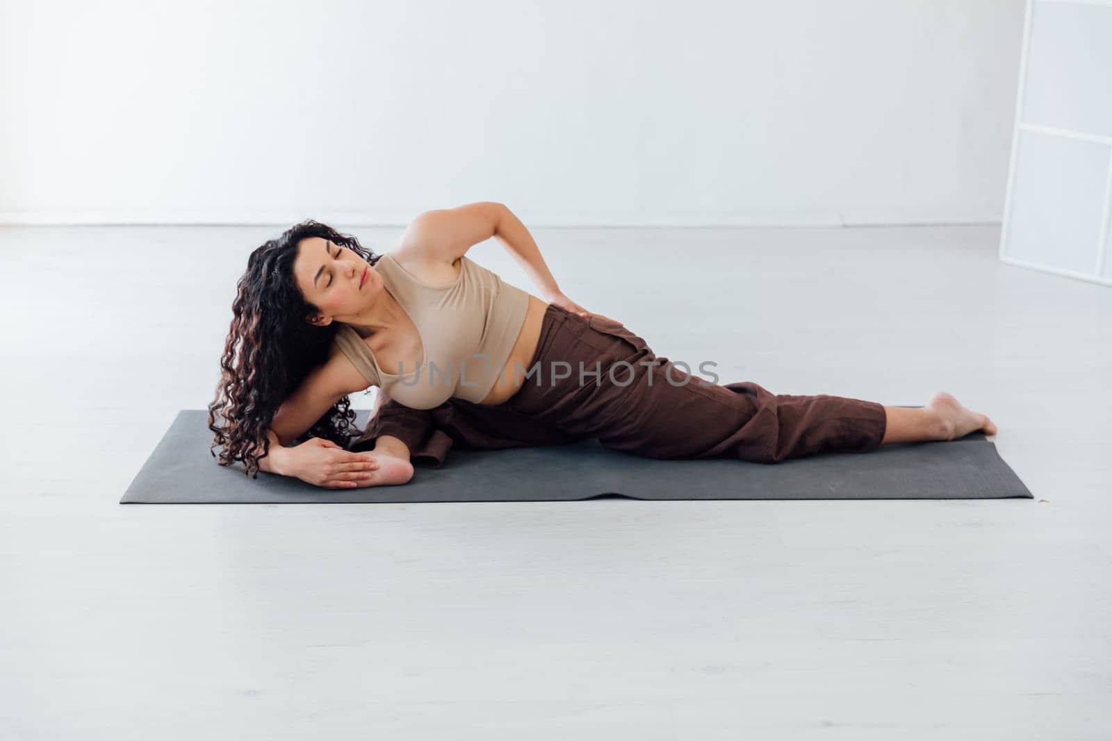 Beautiful sporty curly woman doing yoga asana fitness exercises on the floor by Simakov