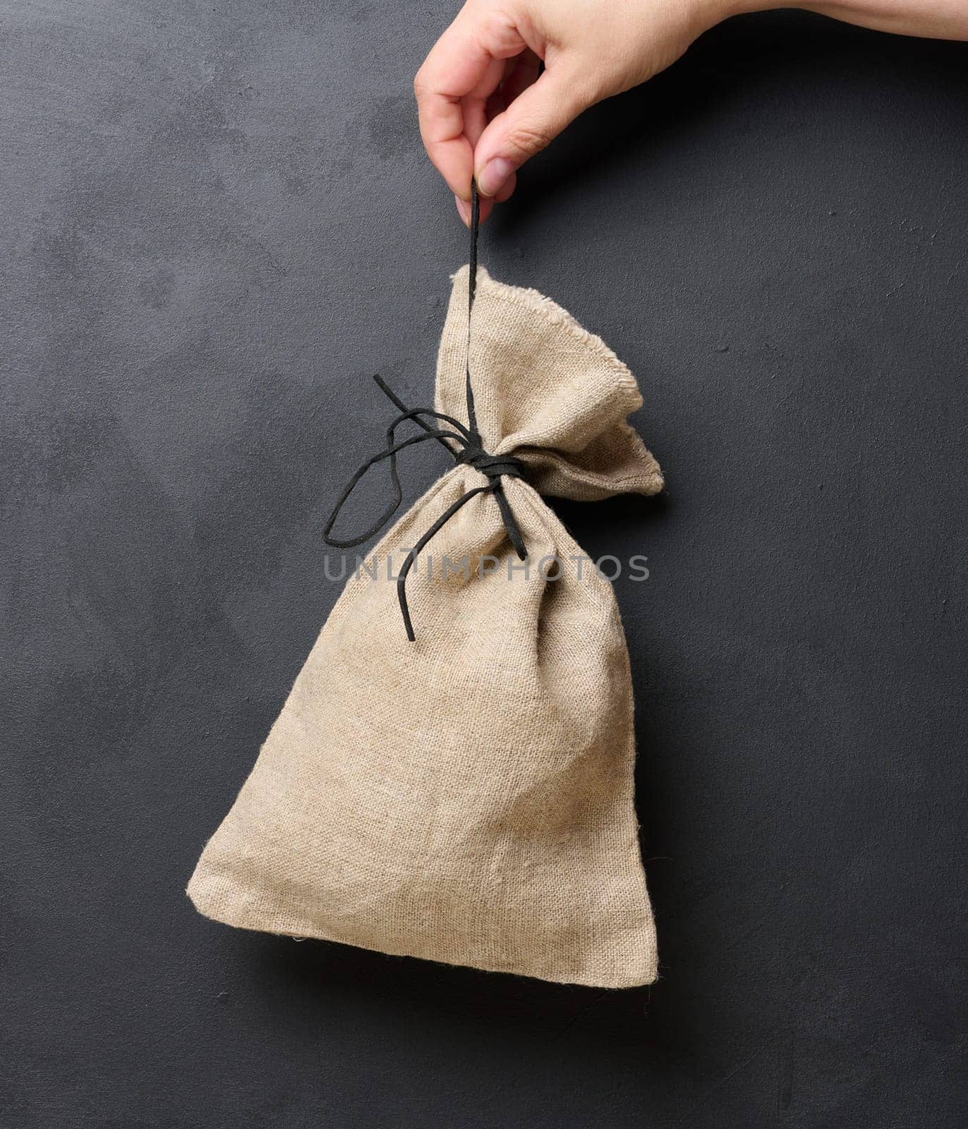 A woman's hand holds a canvas bag on a black background, the concept of a subsidy, help