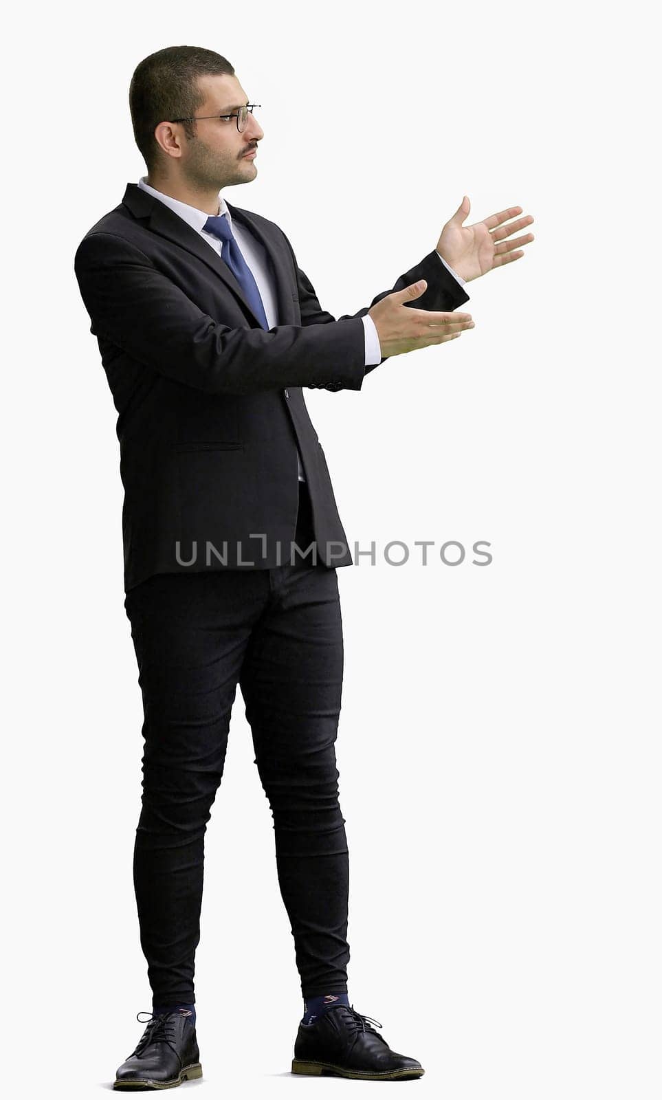 young man in full growth. isolated on a white background shows hands to the side by Prosto