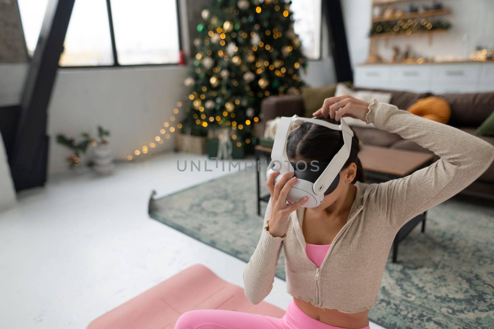 Engaged in yoga, the girl wears pink sportswear and virtual reality glasses. High quality photo