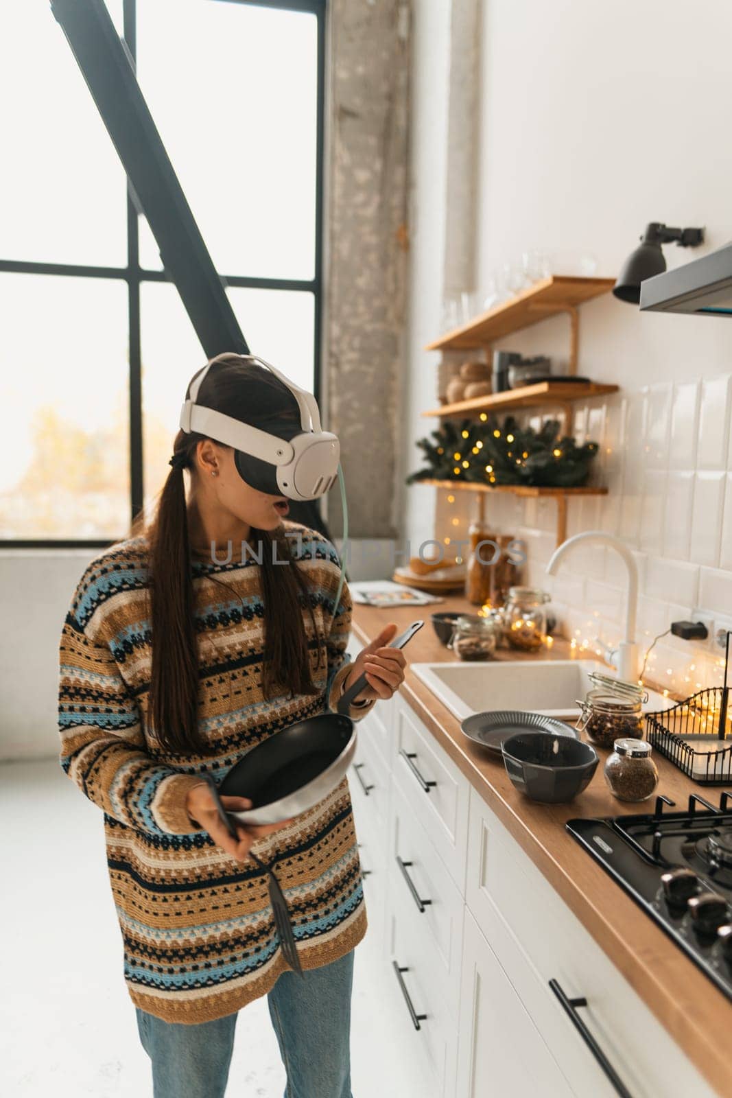 A beautiful, stylish girl is cooking according to a Christmas recipe in a virtual reality headset in the holiday kitchen. High quality photo
