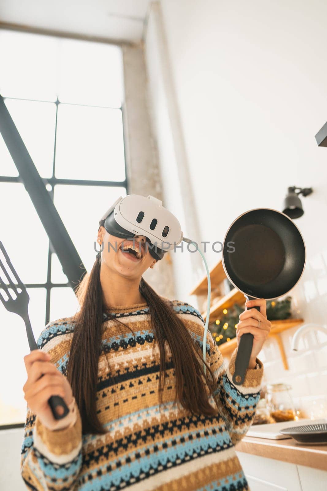 A young, beautiful woman cooks in the kitchen wearing a virtual reality headset. High quality photo