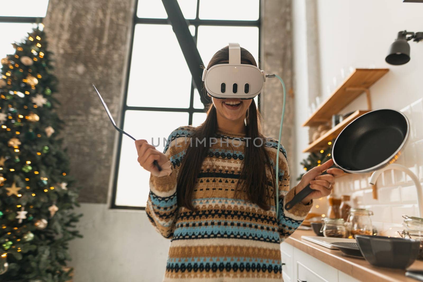 In the kitchen, a lovely young lady cooks while donning a virtual reality headset. High quality photo