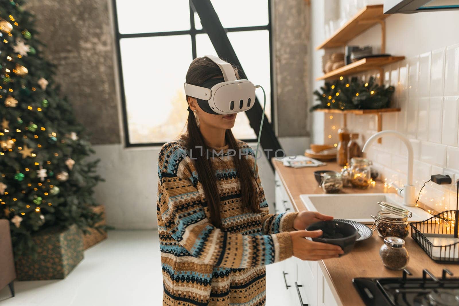 Engaged in holiday cooking, a beautiful and stylish girl uses a virtual reality headset for the recipe in the Christmas kitchen. High quality photo