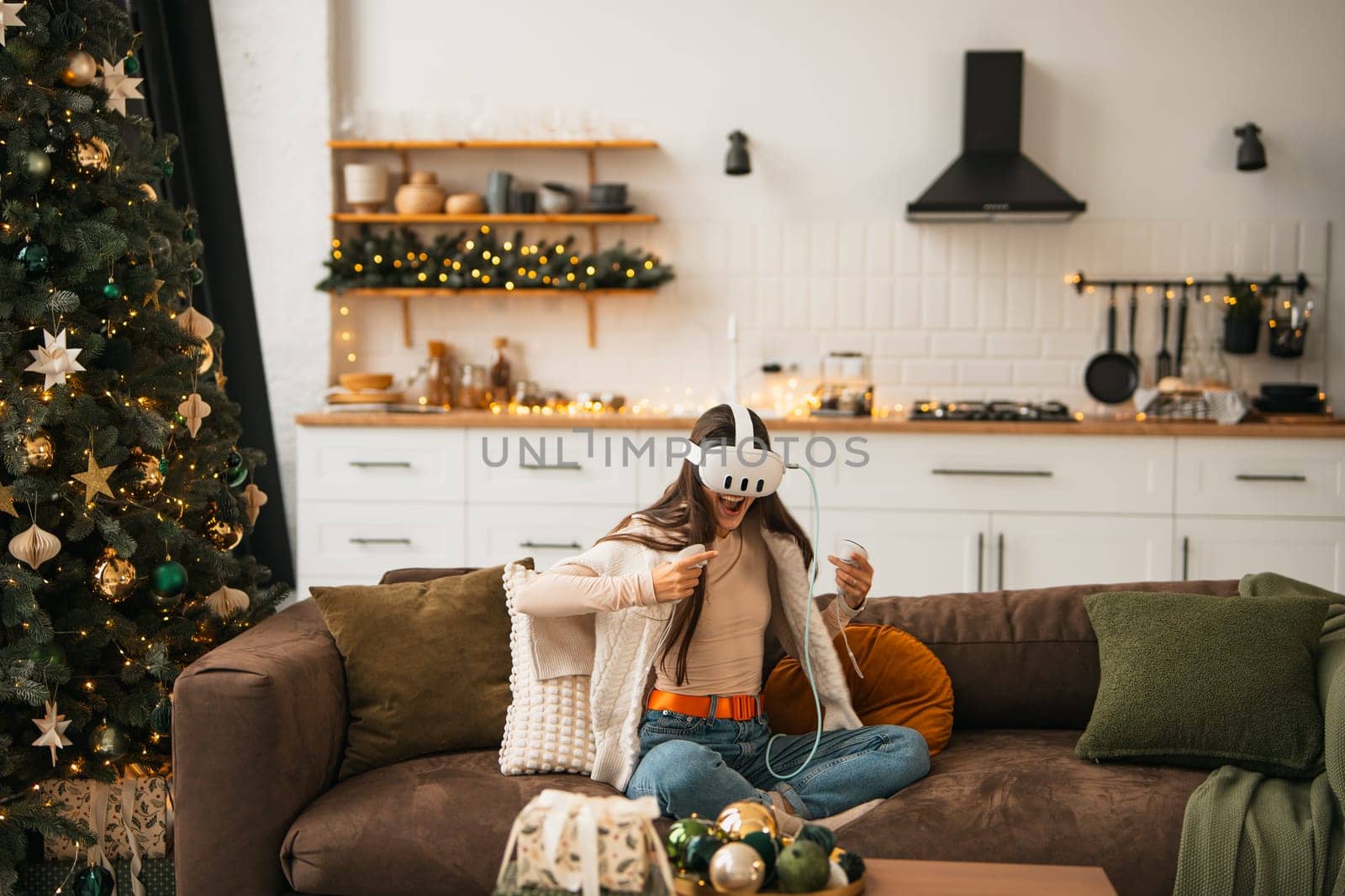 In a cozy holiday ambiance at home, a fashionable young lady uses a virtual reality headset. High quality photo