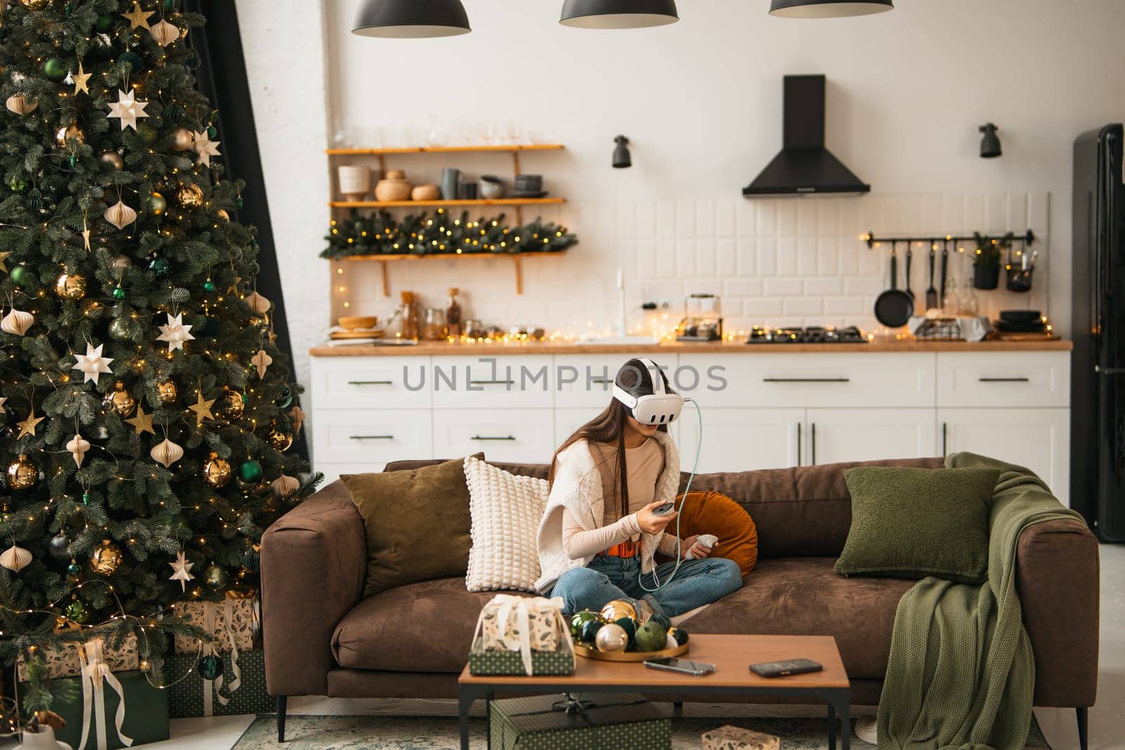 Amidst a warm Christmas ambiance at her place, a stylish young woman is seen in a virtual reality headset. High quality photo