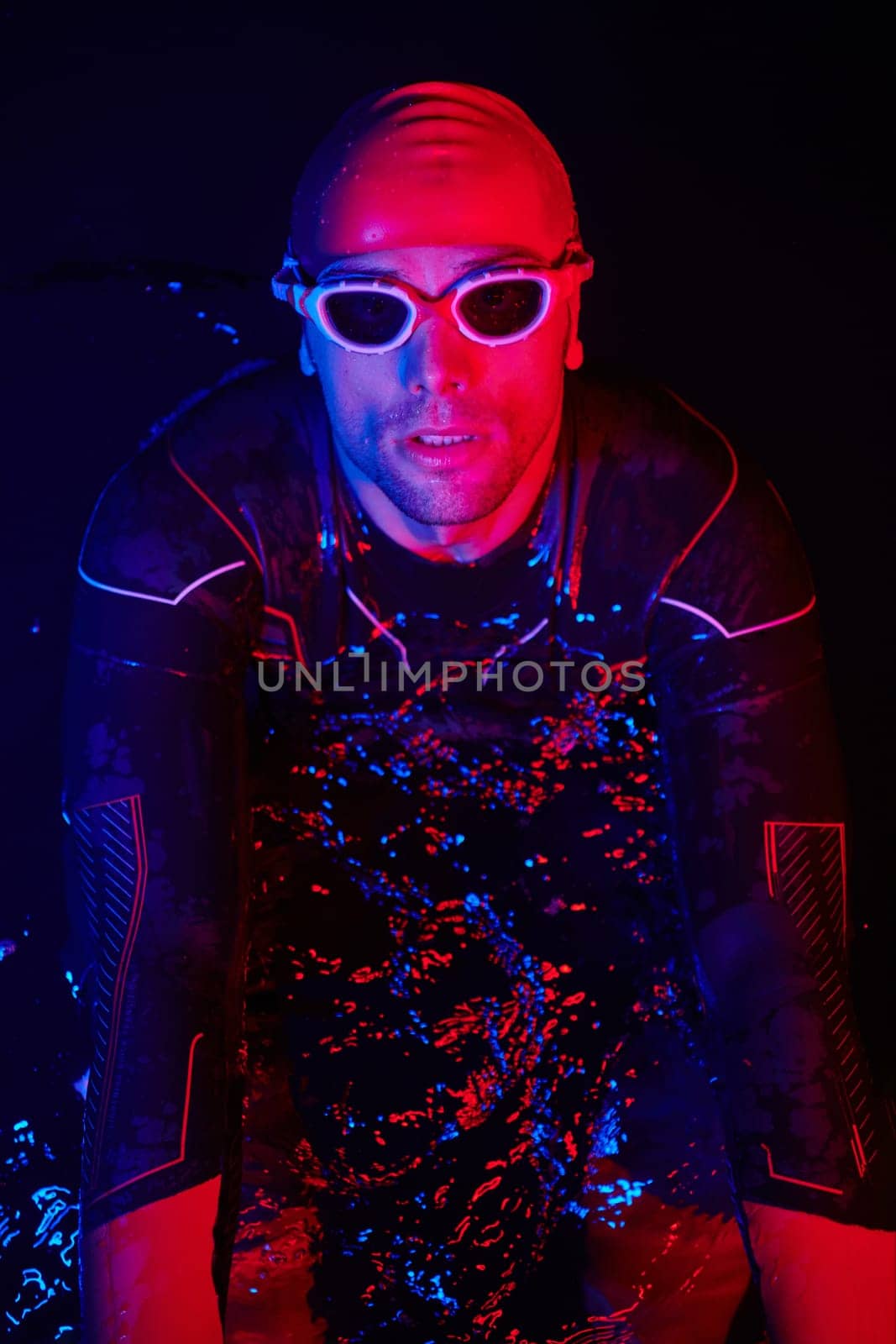 authentic triathlete swimmer having a break during hard training on night neon gel light by dotshock